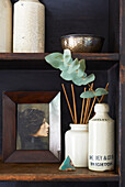 Incense sticks with vintage ceramic storage jars on wooden shelves in Hastings home, East Sussex, England, UK