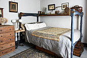 Blue painted four-poster bed with embroidered fabric and wooden chest in Hastings cottage, East Sussex, England, UK