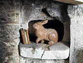 Wooden rabbit and three books on stone shelf