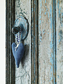 Blue loveheart hangs on lightswitch with ageing paint in Gloucestershire farmhouse, England, UK