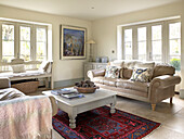 Leather sofa with painted coffee table on patterned rug in seating area of Gloucestershire farmhouse, England, UK