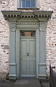 Green paintwork on front door of stone townhouse in Laughame, Wales, UK