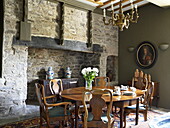 Wooden dining table with exposed stone fireplace in townhouse in Laughame, Wales, UK