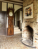 Grandfather clock and brick fireplace in timber framed country house Suffolk, England, UK