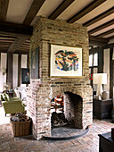 Exposed brick fireplace in open plan drawing room timber framed country house Suffolk, England, UK