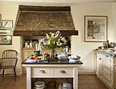 Schnittblumen in einer Küche mit freiliegendem Schornstein aus Backstein in einem Landhaus in Suffolk, England, UK