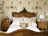 Geschnitztes antikes Bett und Blumentapete in einem Landhaus in Suffolk, England, UK