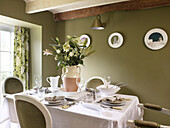 Vase of lilies as centrepiece on dining table in Welsh cottage, UK