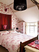 Toile de Jouy-Tapete und gemusterte Bettdecke auf einem Bett in einem walisischen Cottage, UK