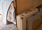 Vintage suitcases at foot of wicker bed in Shropshire chapel conversion England, UK