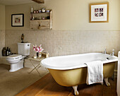 Freestanding bathtub in part-carpeted part-floored bathroom of Gloucestershire farmhouse England UK