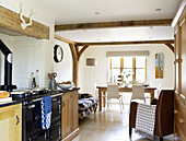 Black range oven in open plan kitchen with dining area in Gloucestershire cottage England UK