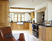 Brown leather armchair in open plan kitchen of Gloucestershire cottage England UK