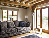 Floral patterned sofa in beamed living room of Gloucestershire cottage England UK