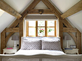 Bed at window in attic conversion of Gloucestershire cottage England UK
