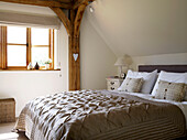 Quilted bed cover in sunlit timber-framed bedroom of Gloucestershire cottage England UK
