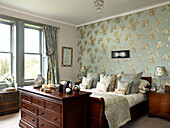Gold floral wallpaper in bedroom with polished wooden furniture in city of Bath home Somerset, UK
