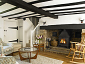 Rocking chair at fireside of wood burning stove in beamed living room in Buckinghamshire cottage England UK
