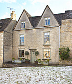 Stone terraced house exterior with pitched attic windows in Tetbury, Gloucestershire, England, UK