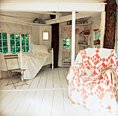 Weiß getäfeltes Baumhaus mit Bett und Stuhl