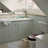 Neutral painted and wood paneled small attic bathroom with eaves