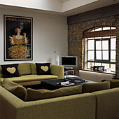 Warehouse conversion apartment living room with green sofas