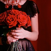 Woman in a black dress holding a bunch of red roses
