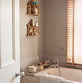 Contemporary neutral bathroom with gold shelves and toiletries
