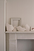 Display of white home wares on a white mantelpiece in a living room