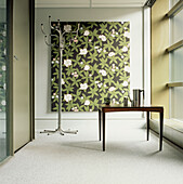 Contemporary hallway with metal coat stand wooden table green floral canvas print glass walls and neutral decor