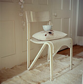 Bemalter Vintage-Stuhl mit Kissen auf einem Teppich aus Tierfell in einer neutralen Farbe