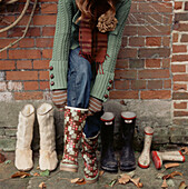 Young woman putting Wellington boots on outside in the garden