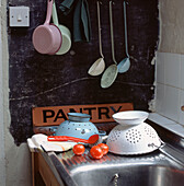 Emaillegeschirr und -utensilien zum Trocknen auf einem Abtropfbrett in der Küche
