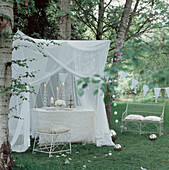 Romantisch gedeckter Tisch in einem grünen, von Bäumen gesäumten Garten