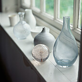 Collection of glass and ceramic home wares on a window sill