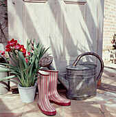 Watering can pot plant and Wellington boots in a doorway of a modern country home
