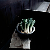Bowl of freshly picked leeks on a bench