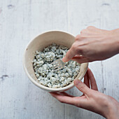 Woman's hands mashing ingredients in a ceramic mixing bowl