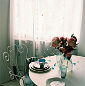 Verschnörkelter Metall-Esszimmerstuhl mit rundem Esstisch und einer Blumenauslage