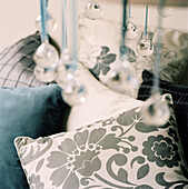 Detail of patterned fabric cushions and glass Christmas decorations