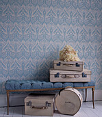 Hallway with blue patterned wallpaper upholstered vintage bench and suitcases