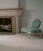 Neutral coloured carpeted living room with open fire and upholstered vintage style chair