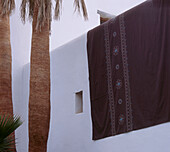 Weißes Haus im mediterranen Stil mit Bettwäsche, die an der Wand lüftet
