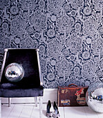 Bold patterned wallpaper in a hallway with upholstered chair shoes suitcase and disco balls