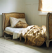Upholstered vintage style single bed with embroidered bed linen