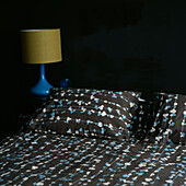 Double bed with patterned bed linen and dark painted walls