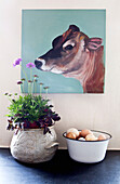 Canvas of a cow's head with a bowl of eggs and houseplant, detail, UK