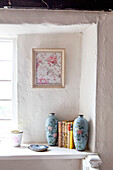 Ornamental vases and books on window ledge in whitewashed UK home, detail