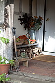 Firewood and doormat with garden fork in porchway of farmhouse, United Kingdom