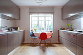 DSW chairs at window in galley kitchen of contemporary London home England UK